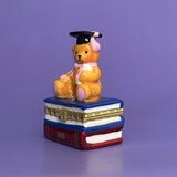 Side view of hand-painted graduation bear trinket box showing glossy glaze and stacked-book base.