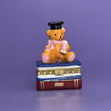 Graduation Bear Trinket Box — hand-painted ceramic bear in cap and scarf sitting on blue and red books, with gold trim