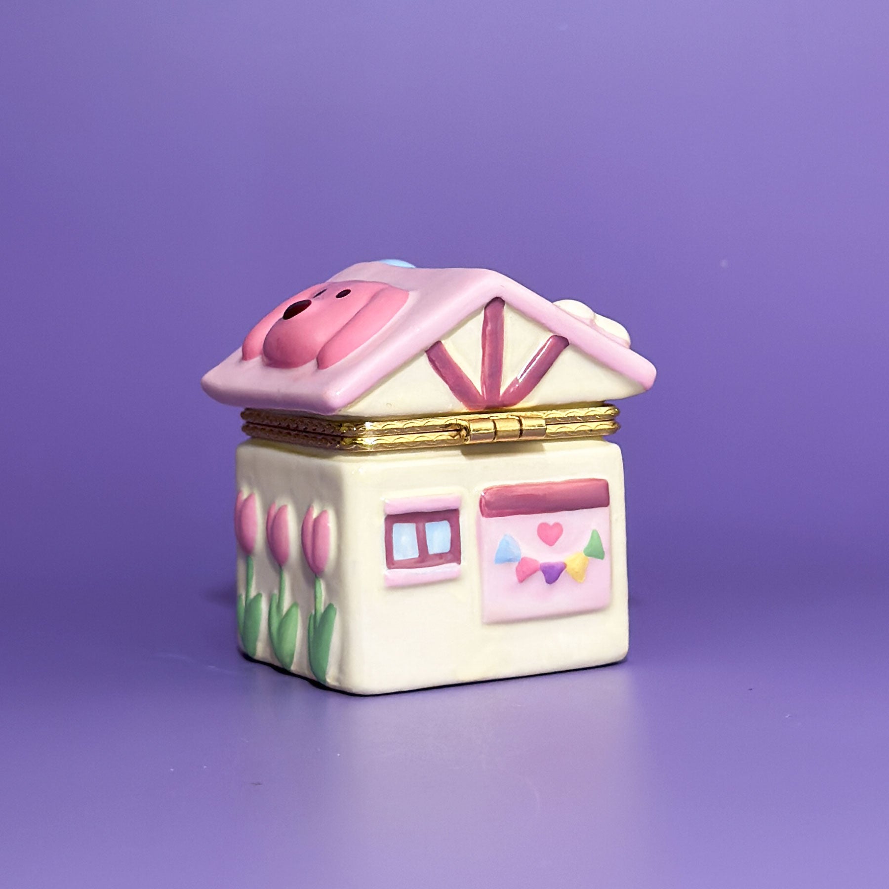 Angled view of hand-painted dog room trinket box with tulip flowers, pink roof, and gold clasp.