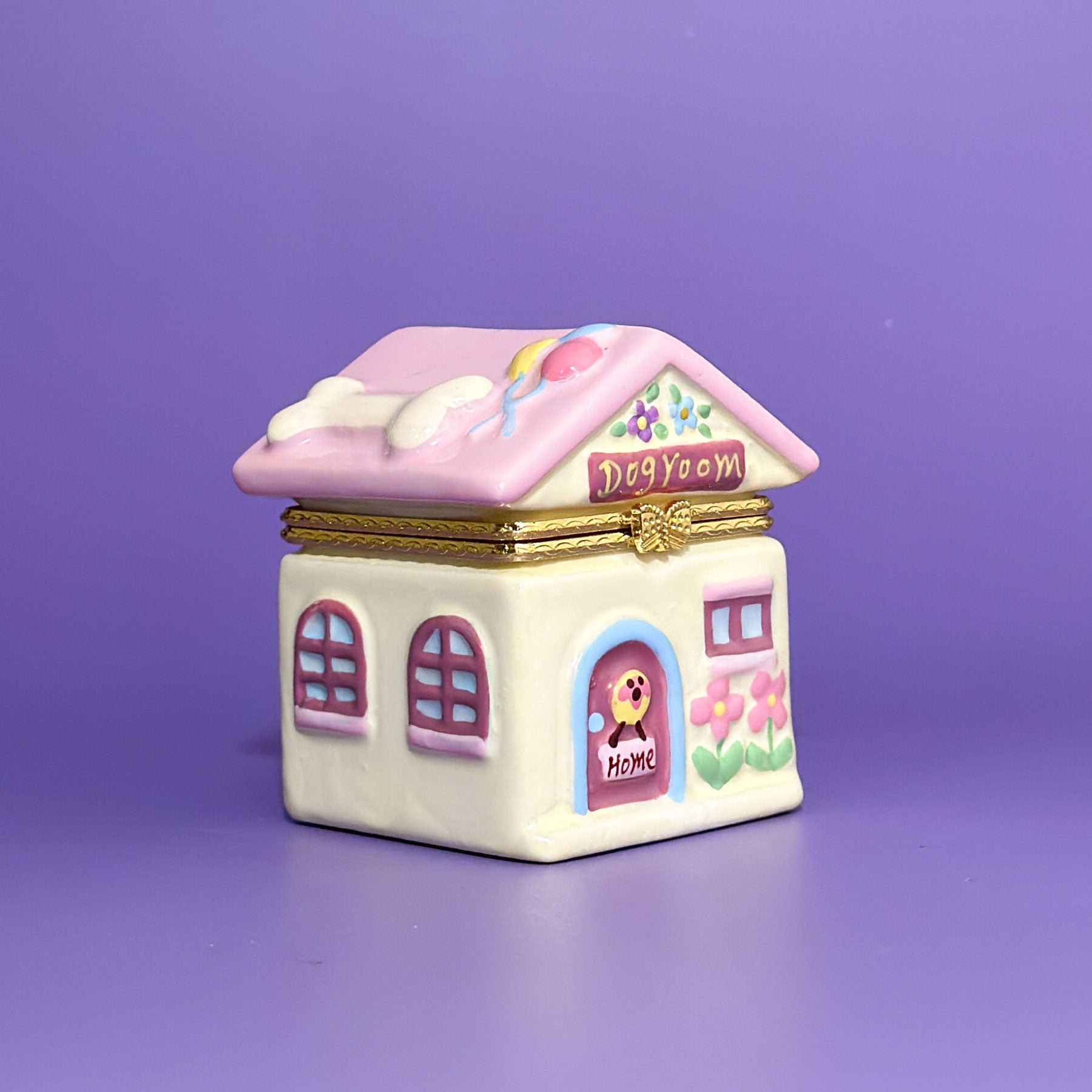Front view of ceramic dog room trinket box with pink roof, floral details, and a cheerful dog at the front door.