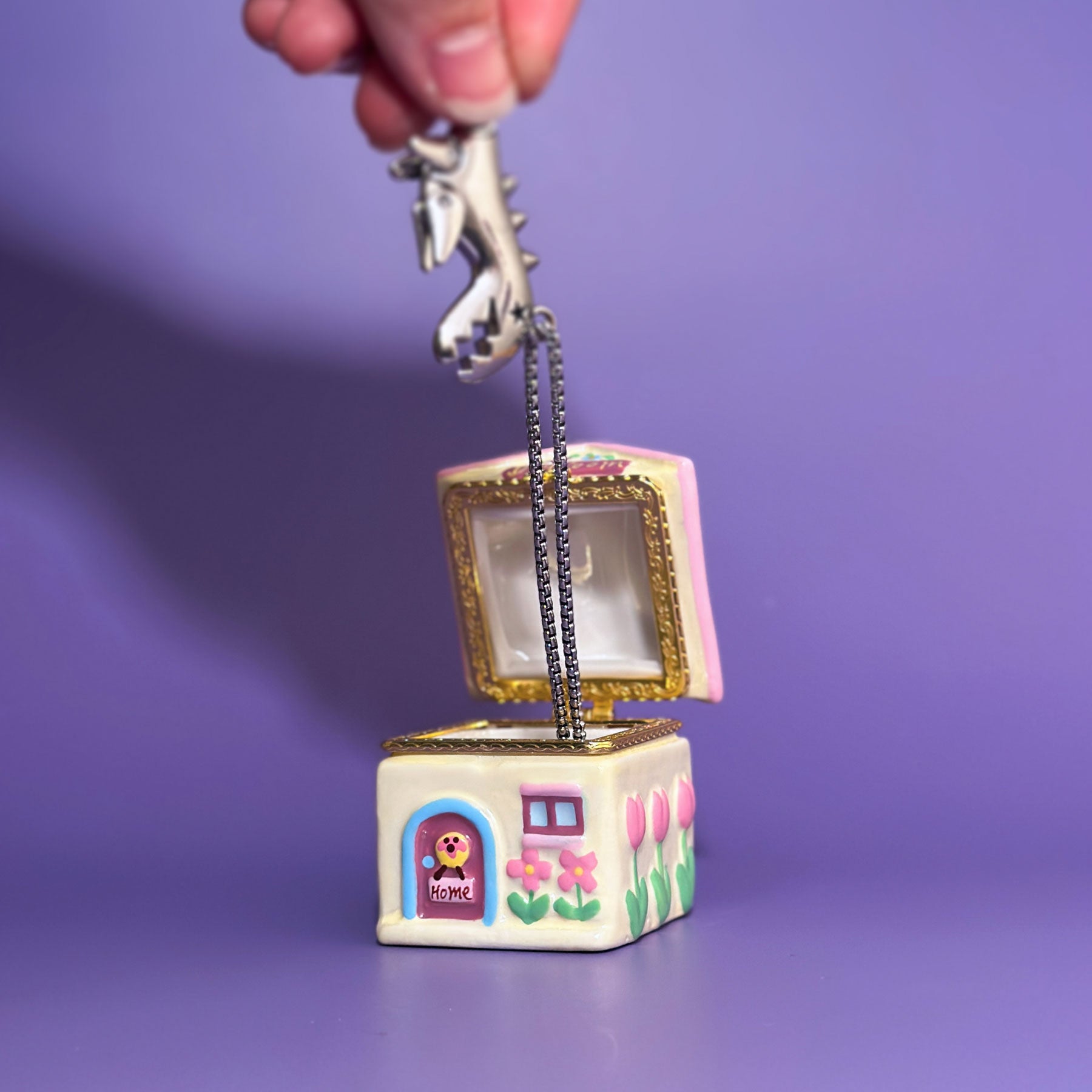 Open ceramic dog house trinket box showing jewelry storage compartment with gold metal hinge.