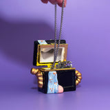 Hand opening vintage sewing machine trinket box to show white ceramic interior and keychain.